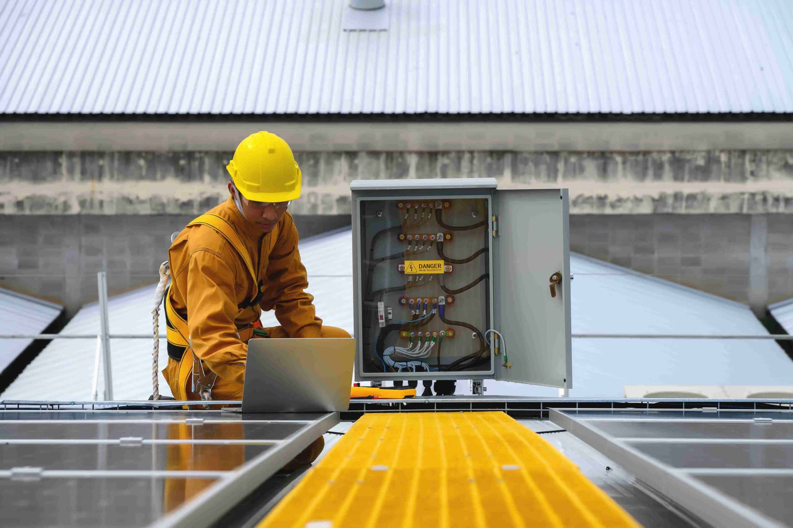 A man in yellow uniform and safety cap working on a laptop
